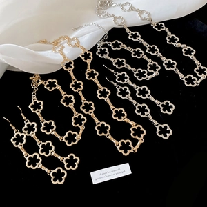 Close-up of gold and silver four-leaf clover jewelry set on a black and white fabric