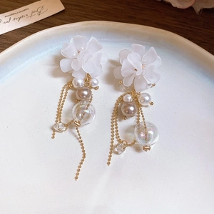Détail de boucles d'oreilles fleurs avec pampilles de perles sur plateau céramique