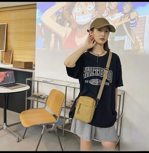 Detailed view of a khaki nylon crossbody bag styled with a matching baseball cap on model