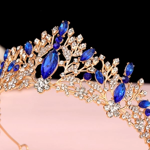 Detailed close-up of golden crown featuring blue gemstones and intricate floral rhinestones
