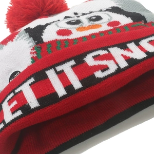 Detail of LED knit Christmas hat featuring a penguin pattern and Let It Snow text