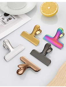 Detailed view of colorful stainless steel food clips in five metallic finishes on a table