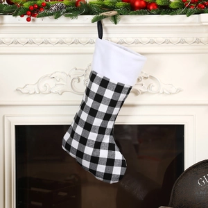 Classic black and white buffalo plaid Christmas stocking with white plush cuff on fireplace