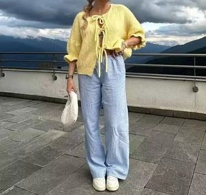 Detail of yellow tie-front cardigan with ruffled cuffs and blue striped wide-leg pants