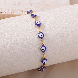 Detail of blue evil eye beads with gold chain links on a white display cylinder