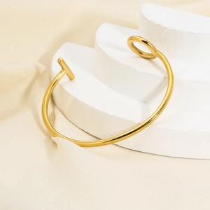 Macro shot of minimalist gold stainless steel bracelet with T-O clasp detail