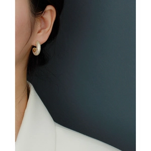 Close-up of elegant gold pavé hoop earrings worn on a model in a luxury setting