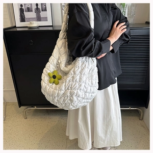 Detailed side view of white quilted bubble tote bag with a green flower charm