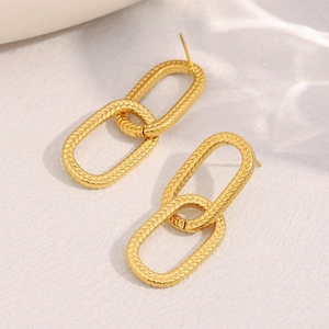 Dettaglio di orecchini in acciaio placcati oro 18K con trama testurizzata a serpente