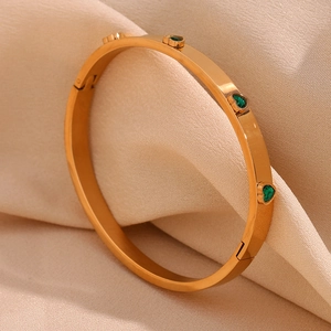 Detailed view of an 18K gold plated bangle featuring green heart-shaped zircon stones