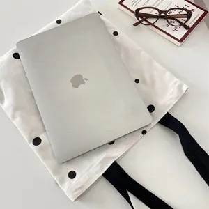 Spacious white canvas tote bag with black polka dots showing laptop storage capacity