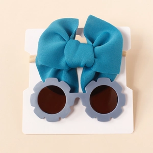 Dettaglio del set fascia con fiocco blu e occhiali da sole a fiore grigi