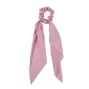 Detailed view of pink satin scrunchie with long ribbon showing soft silky texture