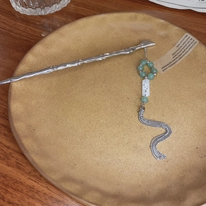 Detail of silver hair stick with bamboo shape, green beads and dangling metal tassels