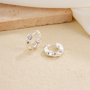 Detailed view of silver hoop earrings with a unique lava texture on a minimalist stone base