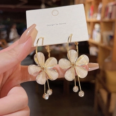 Detail view of flower earrings with cream petals, gold accents, and rhinestone drops
