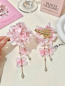 Detail of pink fabric flower hair clip with golden chain tassel and teardrop pearl charms