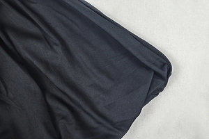 Macro shot of dark pleated fabric texture with delicate vertical folds and soft weave detail