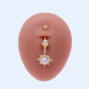 Vue détaillée d'un piercing de nombril doré avec pendentif soleil et cristaux brillants