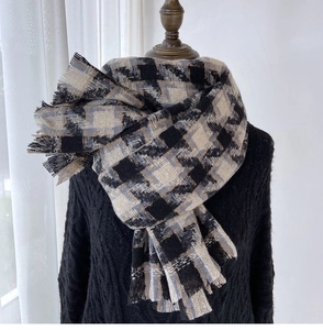 Detailed view of houndstooth scarf texture with fringed edges and soft cashmere-like fabric