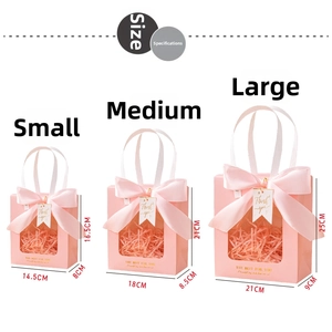 Detail view of pink gift bags with clear window, white ribbon handles and satin bows