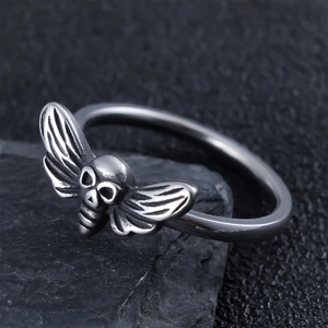Gothic skull moth ring in vintage stainless steel resting on a dark natural rock