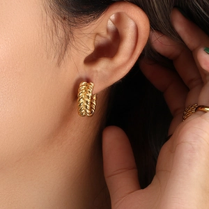 Detailed close-up of C-shaped 18K gold-plated hoop earrings with wheat ear texture