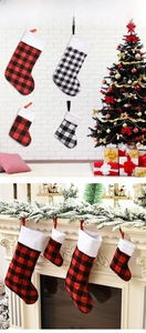 Classic red and black plaid Christmas stockings with plush white trim hanging by fireplace