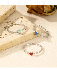 Macro detail of S925 silver twist rings with colorful enamel hearts on stone
