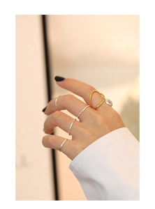 Detail view of irregular gold ring and textured silver bands stacked on finger