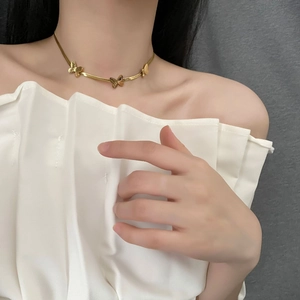 Collier papillon élégant en titane doré avec trois pendentifs porté sur modèle
