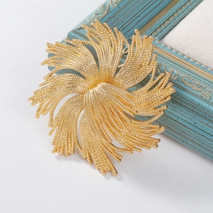 Macro detail of golden vintage fireworks brooch with textured radial floral pattern