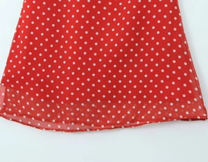 Detailaufnahme von rotem Chiffonstoff mit weißen Punkten und feiner Saumverarbeitung