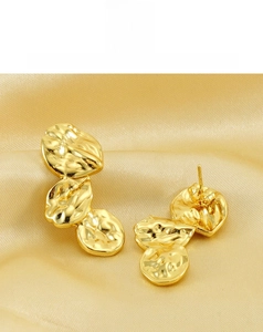 Details von goldfarbenen Ohrringen mit einem kunstvollen unregelmäßigen Falten-Design