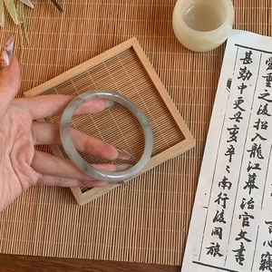 Detail of grey-green glazed glass bracelet with smooth texture in a Zen style setting