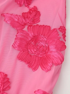 Gros plan sur le tissu d'une robe rose avec broderie florale complexe et texture détaillée