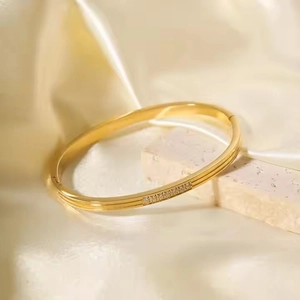Luxurious 18K gold geometric bangle with diamonds on elegant beige silk background