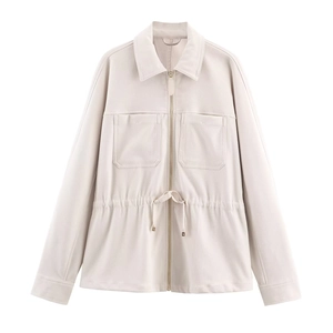 Détail d'une veste beige texturée avec taille à cordon réglable et deux poches utilitaires