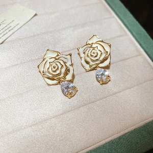Detailed macro view of 18k gold plated rose earrings with white petals and zircon drops