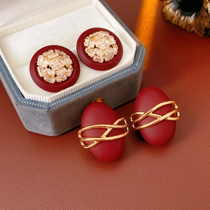 Detail view of red matte earrings in a velvet jewelry box and on a leather surface