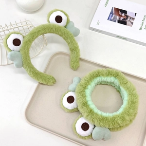 Detail of plush green frog eye headband and scrunchie set with soft faux fur texture