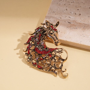 Detailed macro view of retro gold horse brooch with red rhinestones and hollow patterns