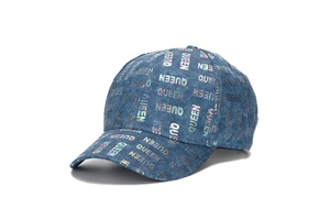 Close-up of navy denim baseball cap with holographic QUEEN pattern and metallic finish