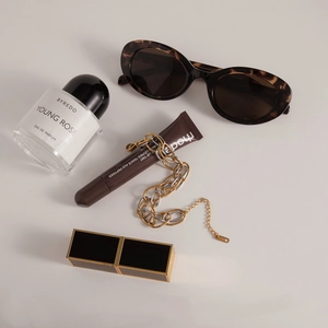 Flat lay of two-tone stainless steel link bracelet with perfume and fashion accessories