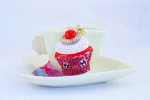 Macro detail of cute cake keychain with pink rhinestones and white enamel cream