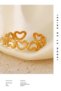 Detailed view of adjustable golden cutout heart ring on beige textured stone surface