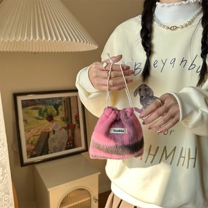 Detail of a pink and brown plaid fleece drawstring bag with a woven brand label