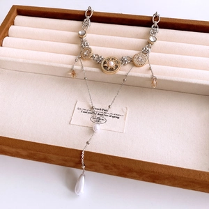 Detailansicht der Vintage-Sonnenmedaille-Halskette mit großer Tropfenperle auf Display