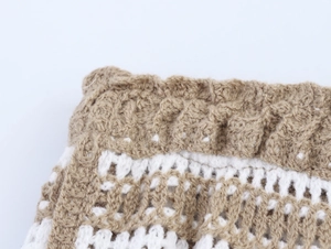 Detailed close-up of khaki and white crochet knit fabric with hollow mesh texture