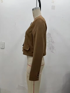 Detail view of brown suede jacket with functional flap pockets and buttoned cuffs